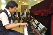 Photo shows Mr Lam enjoying a performance by the school's piano talent Lie Ning-yuen.