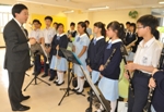 Photo shows Mr Lam chatting with members of the school's marching band.