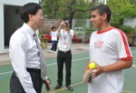 Photo shows Mr Lam chatting with a student during cricket training.