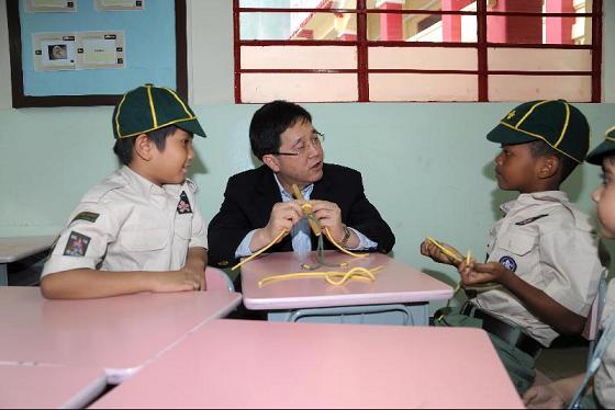 Photo shows Mr Lam chatting with students participating in scout activities.