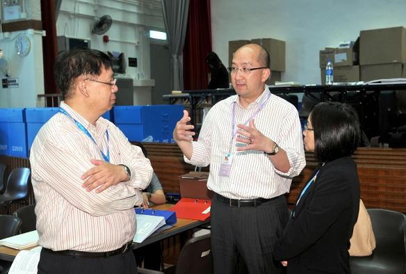 The Secretary for Constitutional and Mainland Affairs, Mr Raymond Tam (second left), chatted with the working staff during his visit to the polling station at the Pok Hong Community Hall, Sha Tin, this afternoon(September 9).