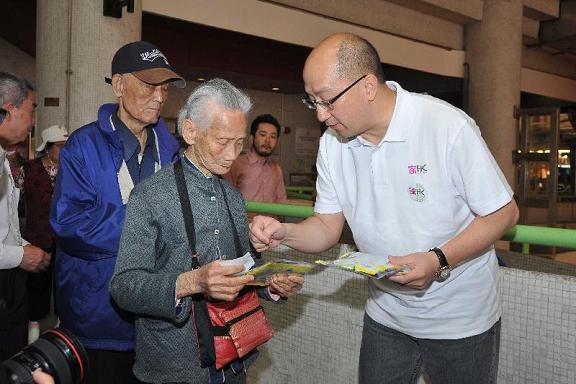 Mr Tam (right) distributes cleansing packs to members of the public.