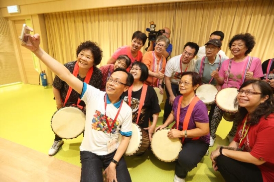 The Secretary for Constitutional and Mainland Affairs, Mr Patrick Nip (front), takes a selfie with a group of elderly people attending a music class at the Po Leung Kuk Lau Chan Siu Po District Elderly Community Centre in Kwun Tong today (July 18).