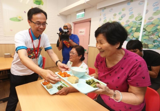 The Secretary for Constitutional and Mainland Affairs, Mr Patrick Nip (left), serves lunch to an elderly person at the Po Leung Kuk Lau Chan Siu Po District Elderly Community Centre today (July 18).