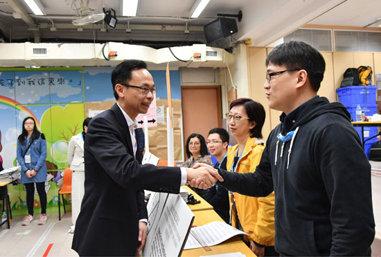 The Secretary for Constitutional and Mainland Affairs, Mr Patrick Nip, visited a polling station for the Central and Western District Council Tung Wah Constituency by-election set up at SKH St. Matthew's Primary School in Sheung Wan this morning (November 26). Photo shows Mr Nip (second left) chatting with staff at the polling station.