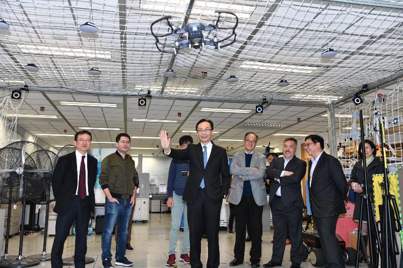 The Secretary for Constitutional and Mainland Affairs, Mr Patrick Nip, and the Under Secretary for Constitutional and Mainland Affairs, Mr Andy Chan (first left), visited Sai Kung District this afternoon (December 28) and toured the robotics institute of the Hong Kong University of Science and Technology. Photo shows Mr Nip (centre) operating a flying drone by hand.